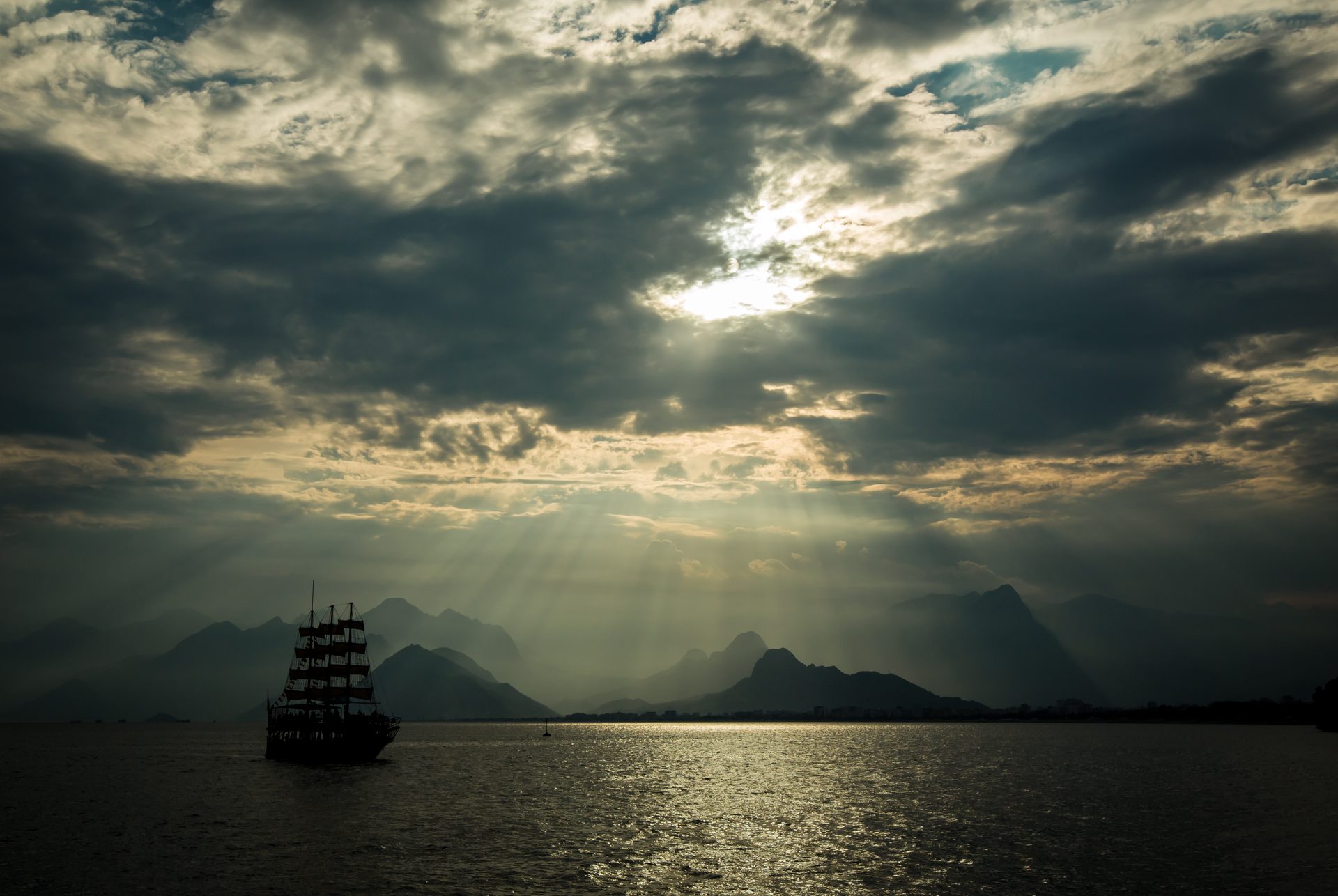 Velero a contraluz con rayos de sol entre las nubes
